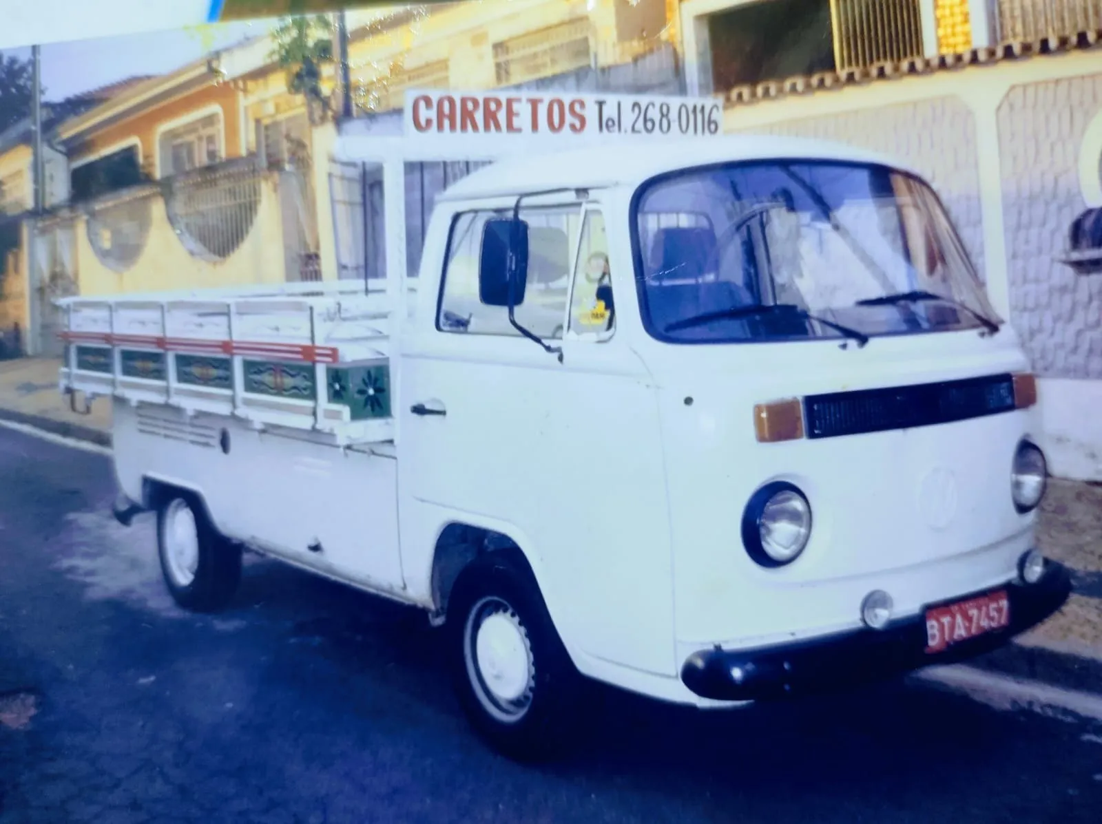 Kombi Pick-up branca de carroceria de madeira com a inscrição Carretos e o telefone 268-0116